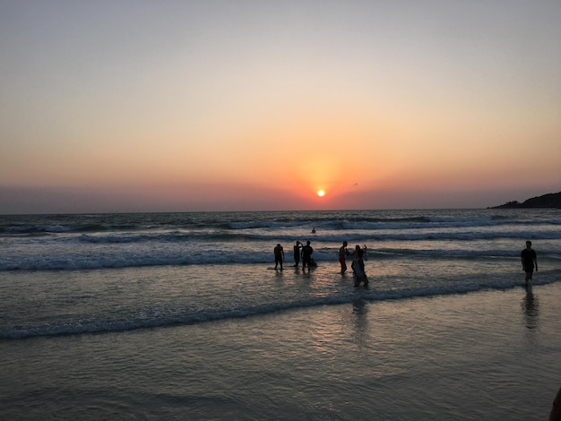 Mensen lopen op het strand bij zonsondergang