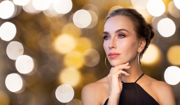 mensen, luxe, sieraden en vakantie concept - mooie vrouw in het zwart dragen van diamanten oorbel en ring over lichten achtergrond
