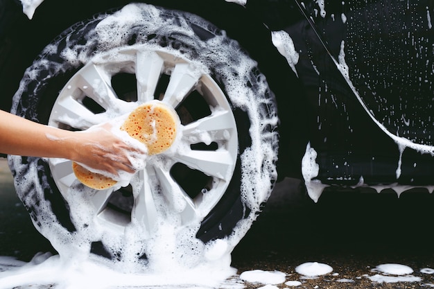 Mensen man met hand gele spons voor het wassen van de auto. wielband schoonmaken. Concept carwash schoon.