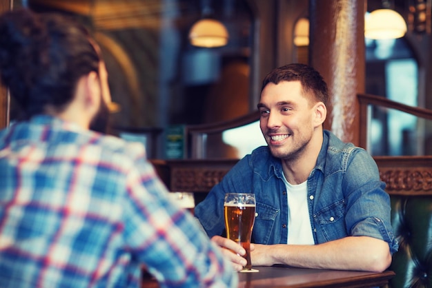 mensen, mannen, vrije tijd, vriendschap en communicatieconcept - gelukkige mannelijke vrienden die bier drinken in de bar of pub