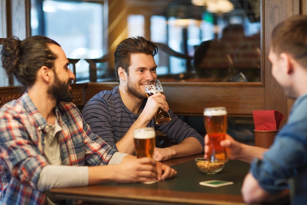 mensen, mannen, vrije tijd, vriendschap en communicatieconcept - gelukkige mannelijke vrienden die bier drinken in de bar of pub