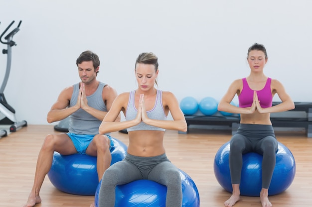 Mensen met gekoppelde handen op oefeningsballen in gymnastiek