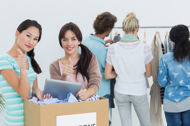 Mensen met kleding donatie en digitale tablet gebaren duimen omhoog