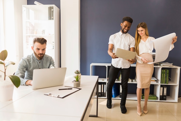 Mensen met laptops en blauwdruk die aan project werken