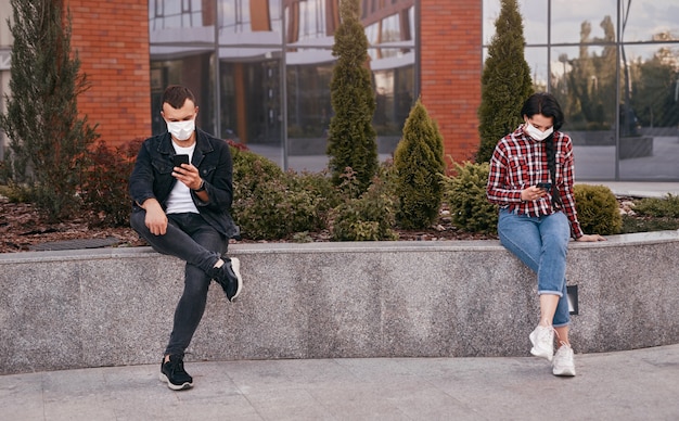 Mensen met maskers die op straat op smartphones browsen