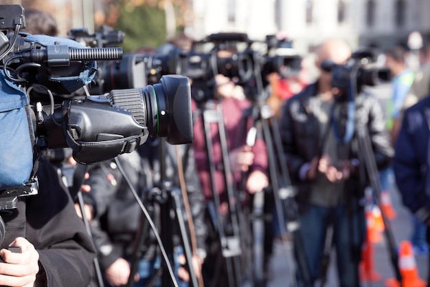 Foto mensen met televisiecamera's staan op de weg.