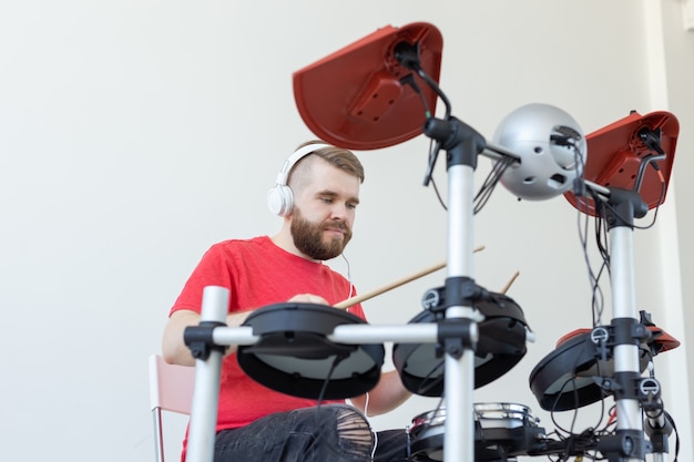 Mensen, muziek en hobbyconcept - jonge mens die de trommel speelt.