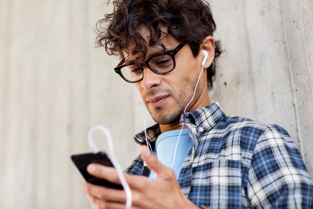 mensen, muziek, technologie, vrije tijd en levensstijl - gelukkige jonge hipster man met koptelefoon en smartphone luisteren naar muziek