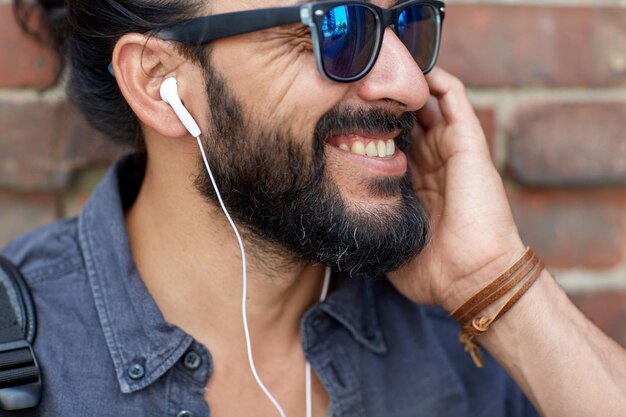 Foto mensen, muziek, technologie, vrije tijd en levensstijl - hipster man met koptelefoon en buiten naar muziek luisteren