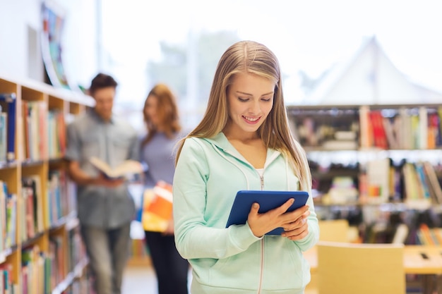 mensen, onderwijs, technologie en schoolconcept - gelukkig studentenmeisje of -vrouw met tablet-pc-computer in bibliotheek