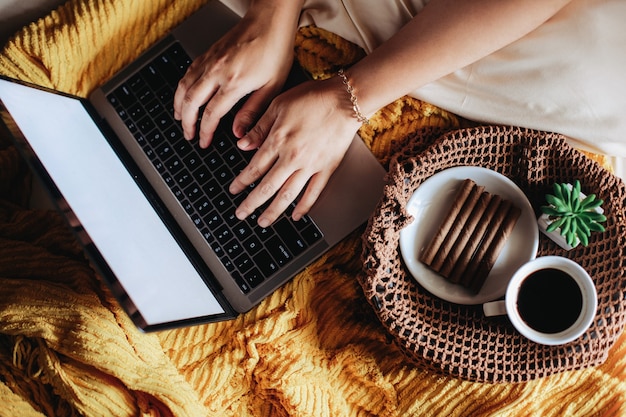 Mensen op een bed met ontbijt en koffie met hand typen op laptop toetsenbord