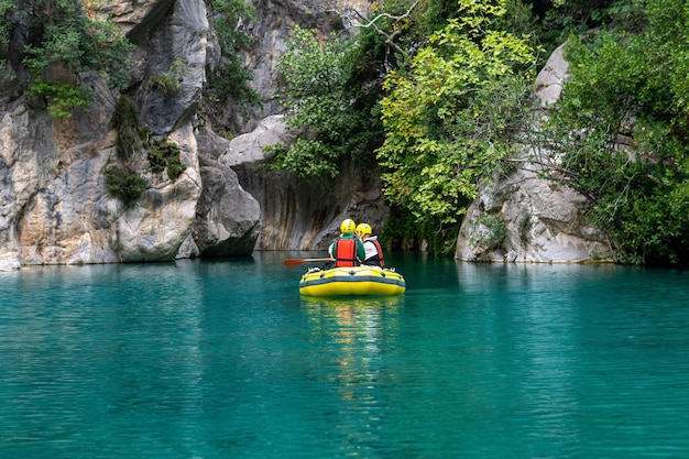 Mensen op een opblaasbare boot drijven door een rotsachtige kloof met blauw water in Goynuk, Turkije