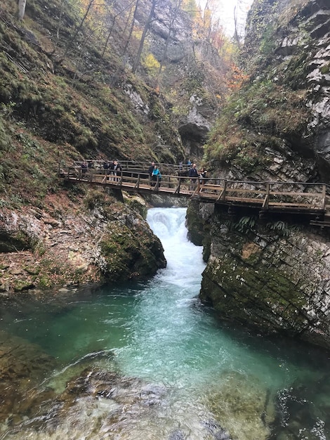 Foto mensen op een voetgangersbrug over een waterval te midden van rotsformaties in het bos