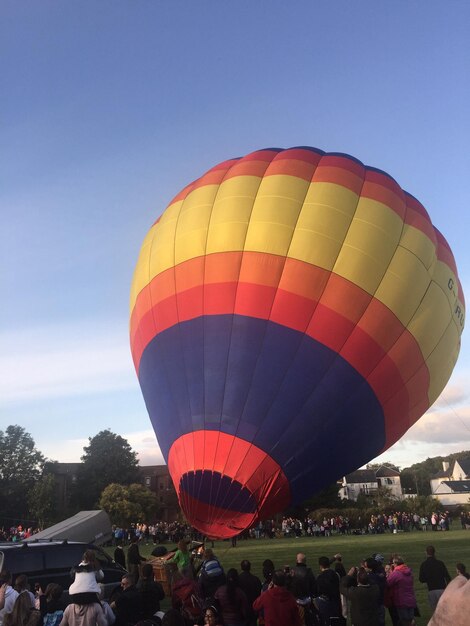 Foto mensen op het gras door een luchtballon tegen de lucht