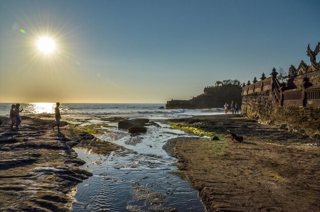 Foto mensen op het strand door tanah lot tegen de lucht