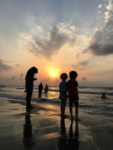 Mensen op zee strand bij zonsondergang met plezier