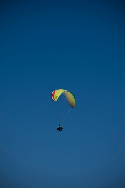 Foto mensen paragliden alleen met blauwe achtergrond zonder wolken.