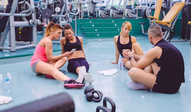 Foto mensen praten terwijl vrienden mobiele telefoons gebruiken in de sportschool