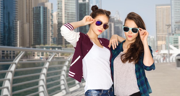 mensen, reizen, toerisme, mode en tieners concept - gelukkig lachende mooie tienermeisjes oe vrienden in zonnebrillen over dubai stadsstraat achtergrond