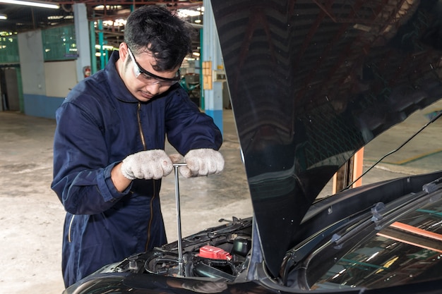 Mensen repareren een auto Gebruik een sleutel en een schroevendraaier om te werken.