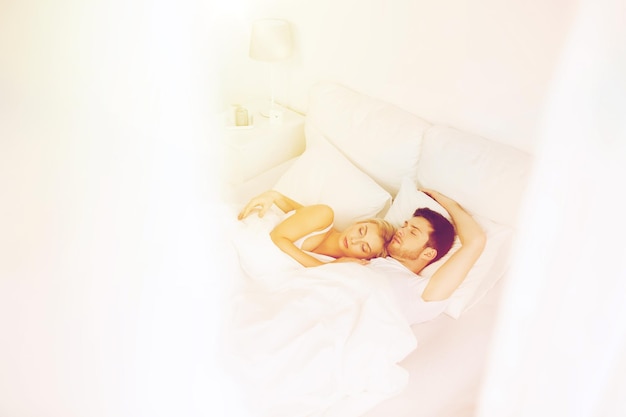 mensen, rust en relaties concept - gelukkig paar slapen in bed thuis