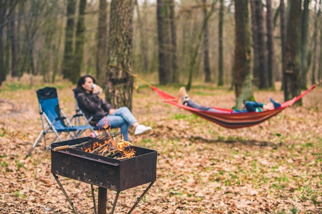 Mensen rusten buiten grill met vuur close-up leggen op hangmat op achtergrond