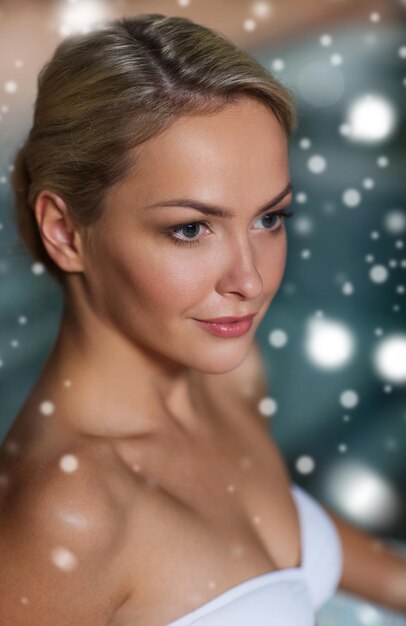 mensen, schoonheid, spa, gezonde levensstijl en ontspanningsconcept - close-up van mooie jonge vrouw in zwembroek bij zwembad met sneeuweffect