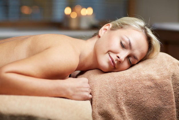 mensen, schoonheid, spa, gezonde levensstijl en ontspanningsconcept - mooie jonge vrouw liggend op massagetafel in spa