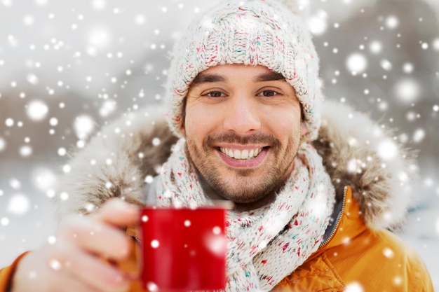 mensen, seizoen, drankjes en vrije tijd concept - gelukkige man met kopje thee buiten in de winter