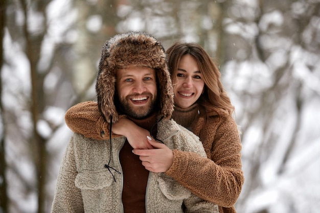 Mensen seizoen liefde en vrije tijd concept gelukkig paar knuffelen en lachen buiten in de winter Paar omhelzen en plezier hebben in besneeuwde winter park