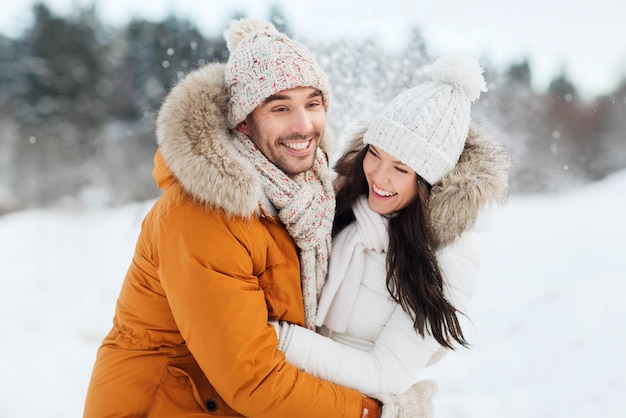 mensen, seizoen, liefde en vrije tijd concept - gelukkig paar knuffelen en lachen buiten in de winter