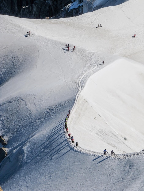 Mensen skiën op een sneeuwbedekt landschap tegen een bewolkte hemel