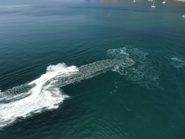 Mensen spelen een jetski in de zee en laten abstracte witte voetafdrukken achter op de luchttop van het water