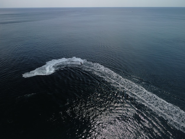 Mensen spelen een jetski in de zee en laten abstracte witte voetafdrukken achter op de luchttop van het water