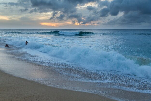 Mensen spelen op het strand met grote golven op de noordkust van Oahu, Hawaii