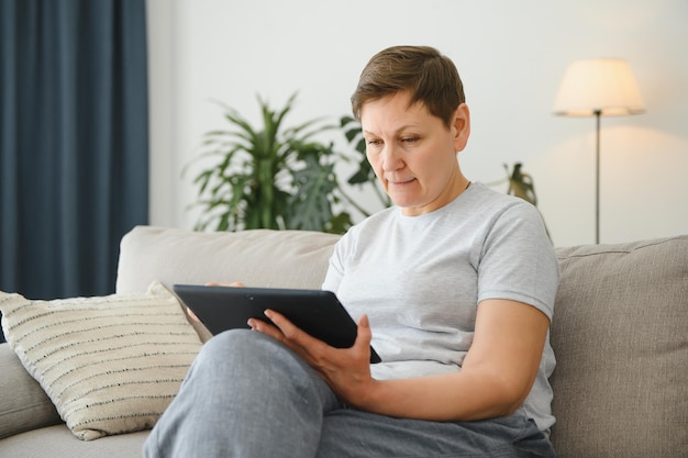 Mensen technologie en internet concept gelukkige vrouw van middelbare leeftijd met tablet pc-computer thuis