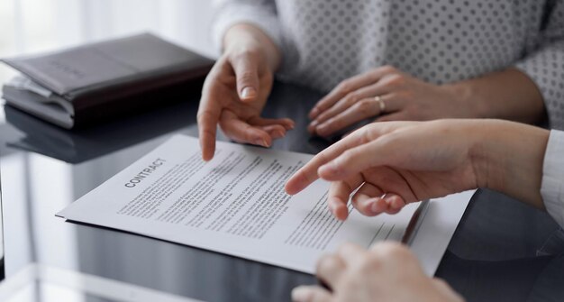 Mensen uit het bedrijfsleven bespreken contract ondertekening deal zittend aan de glazen tafel in kantoor, close-up. Partners of advocaten die samenwerken tijdens een vergadering. Teamwerk, partnerschap, succesconcept.