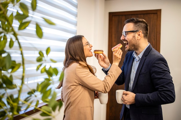 Mensen uit het bedrijfsleven op het werk genieten ervan om samen donuts en koffie te eten