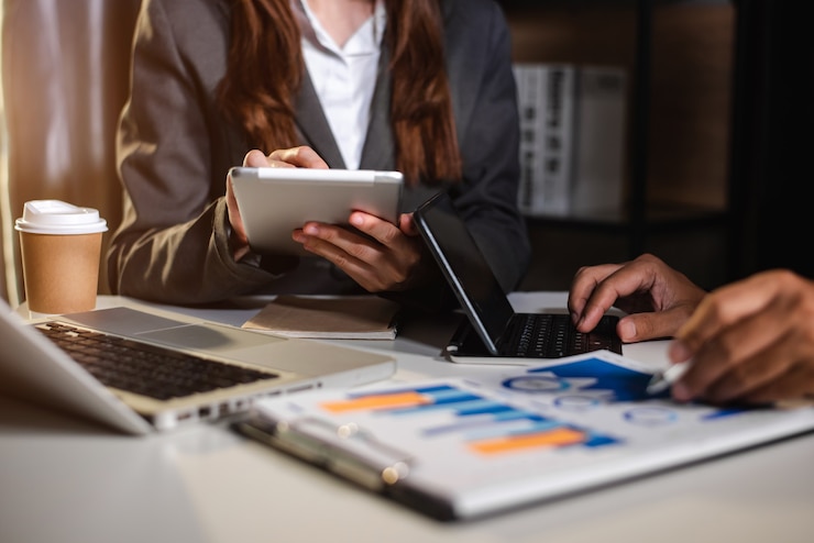 Foto mensen uit het bedrijfsleven praten bespreken met financiële documentgegevens grafieken en grafieken team zakelijke bijeenkomst met smartphone en laptop en digitale tabletcomputer