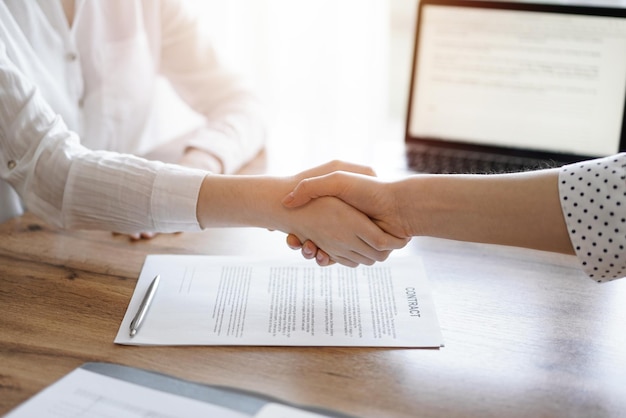 Mensen uit het bedrijfsleven schudden handen boven contractpapieren die net zijn ondertekend op de houten tafel, close-up. Advocaten op vergadering. Teamwerk, partnerschap, succesconcept.