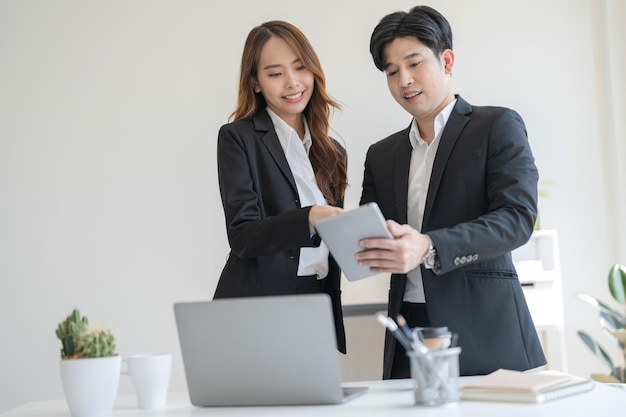 Mensen uit het bedrijfsleven staan samen aan een bureau en praten op hun laptop