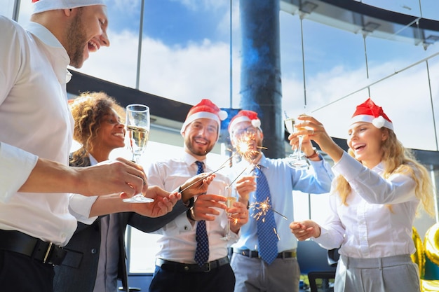 Mensen uit het bedrijfsleven vieren vakantie in een modern kantoor, drinken champagne en hebben plezier in coworking. Prettige kerstdagen en een gelukkig nieuwjaar 2020.