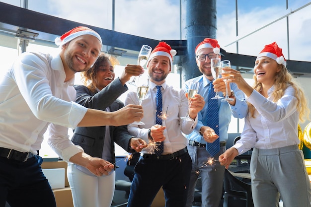 Mensen uit het bedrijfsleven vieren vakantie in een modern kantoor, drinken champagne en hebben plezier in coworking. Prettige kerstdagen en een gelukkig nieuwjaar 2020.