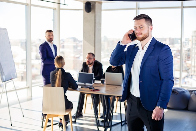 Mensen uit het bedrijfsleven, zakenlieden werken samen in een modern kantoor in een wolkenkrabber met meerdere verdiepingen. De directeur is aan de telefoon. Kantoor werk concept. Selectieve focus