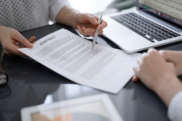 Mensen uit het bedrijfsleven zitten en bespreken contract op kantoor, close-up. Partners of advocaten die samenwerken tijdens een bijeenkomst voordat ze de papieren ondertekenen. Teamwerk en partnerschap