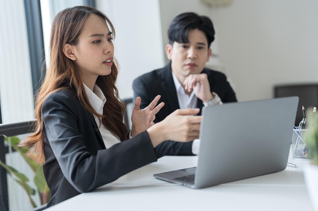 Mensen uit het bedrijfsleven zitten samen aan een bureau met behulp van laptops op kantoor De twee hadden een ernstig bezorgde uitdrukking op hun gezicht terwijl ze samenwerkten