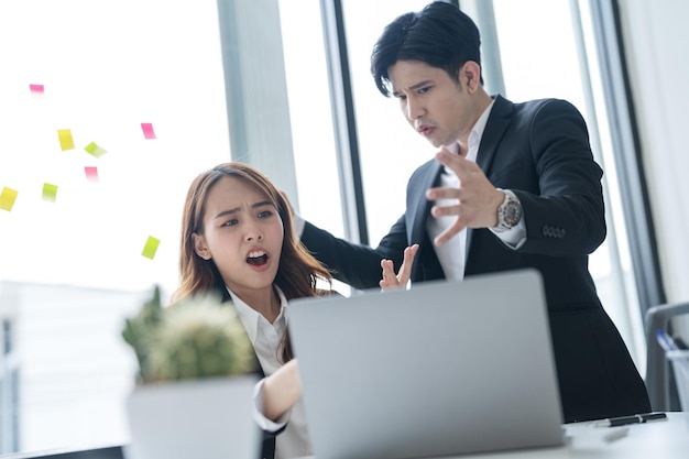 Mensen uit het bedrijfsleven zitten samen aan een bureau met behulp van laptops op kantoor De twee hadden een ernstig bezorgde uitdrukking op hun gezicht terwijl ze samenwerkten