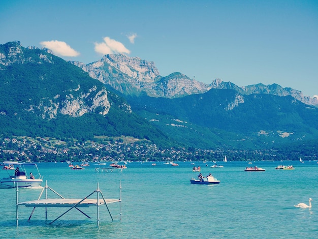 Mensen varen in het meer Annecy tegen de bergen op een zonnige dag