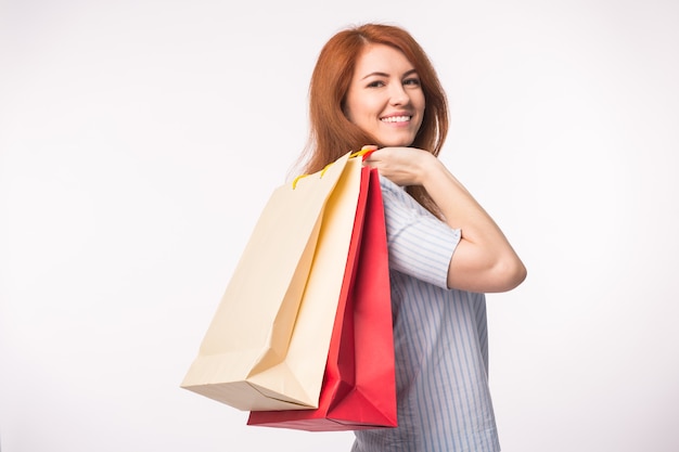 Mensen, verkoop en consumentisme concept. Aantrekkelijke vrouw met rood haar over witte boodschappentassen te houden.