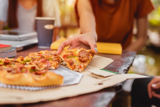 Mensen vieren met de pizza in de hand. Voedsel en vriendschap concept. Leefstijlthema